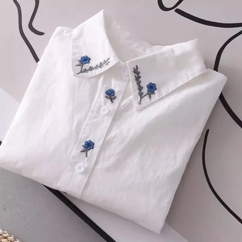 Women's white shirt made of pure cotton, with a fold-down collar, long sleeves, and embroidery.