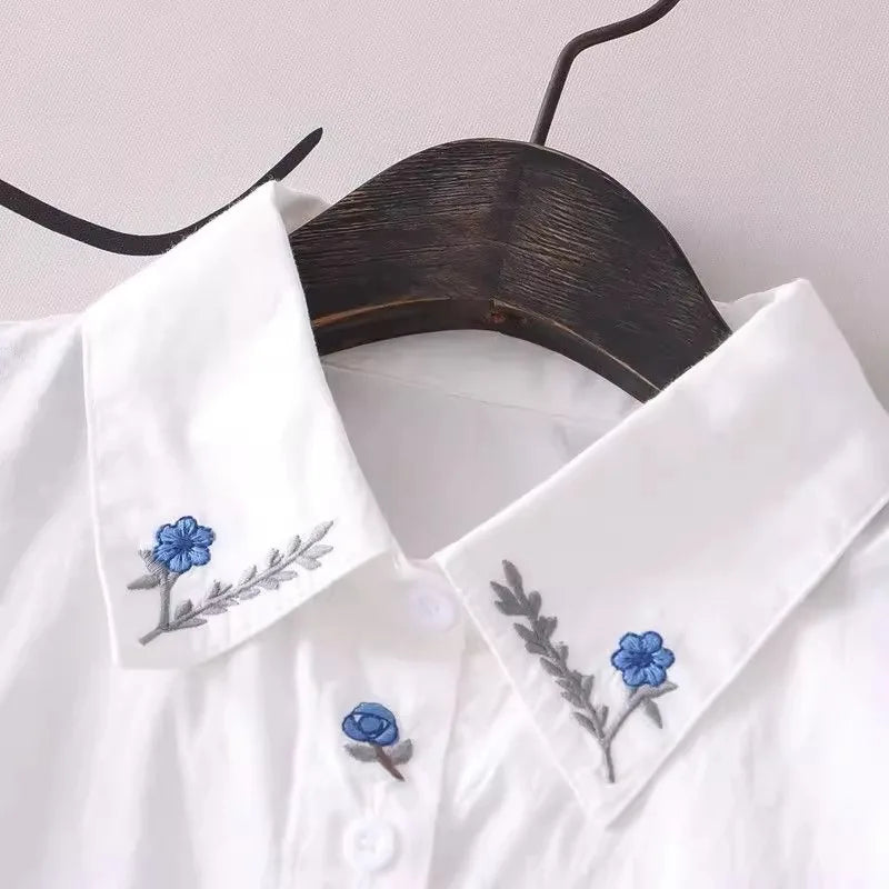 Women's white shirt made of pure cotton, with a fold-down collar, long sleeves, and embroidery.