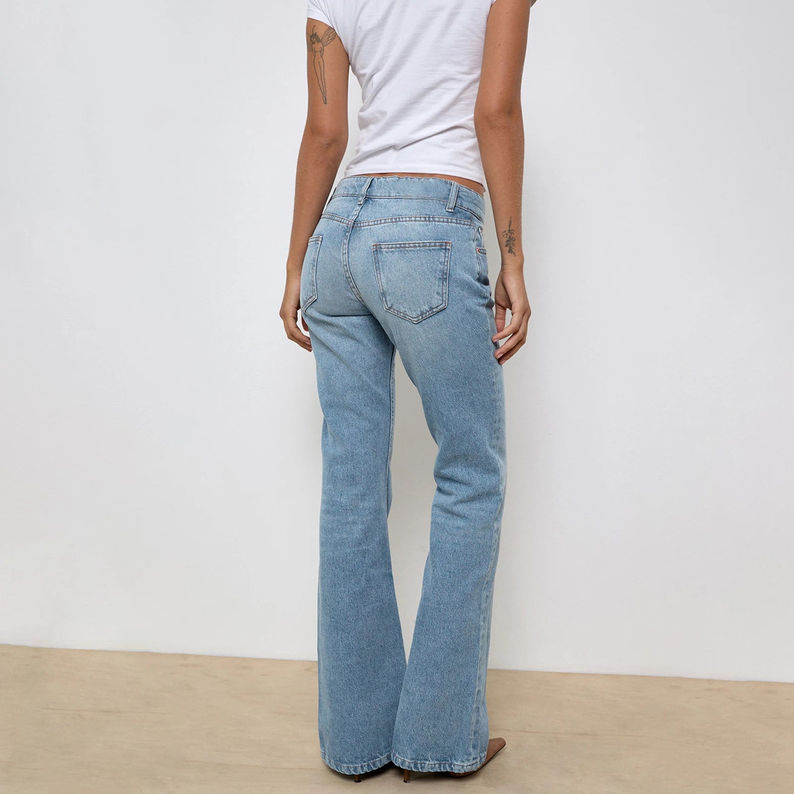 Women's low-waisted jeans with a zipper and buttons, in a solid color, with pockets.